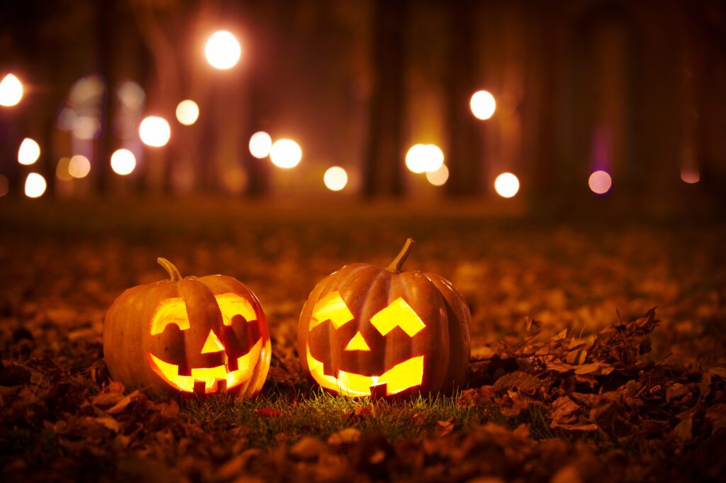 two jack o lanterns with an orange fall background with lights