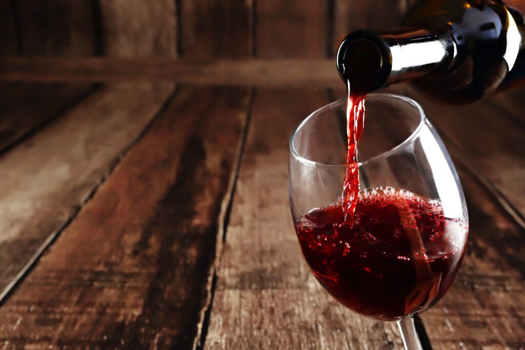 focused shot of a glass of wine being poured on a wooden background