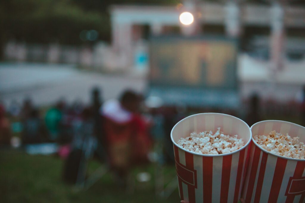 two containers of popcorn facing a movie night on the lawn