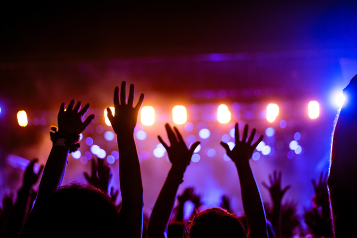 people with hands up at concert with bright colored lights