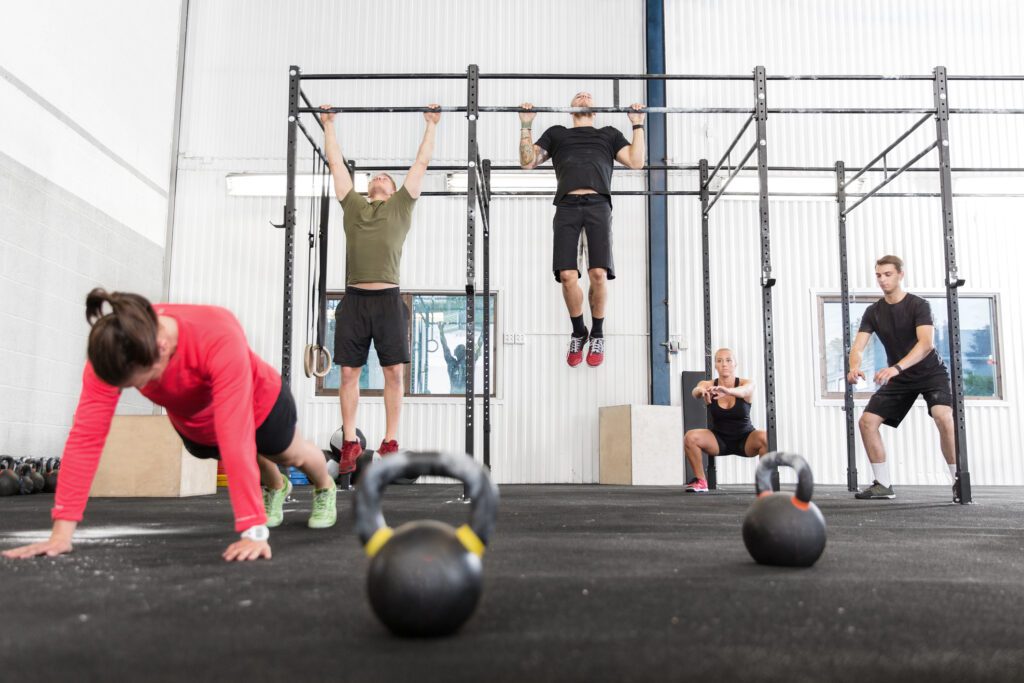 A group training push ups, hang ups and squat at a gym center.
